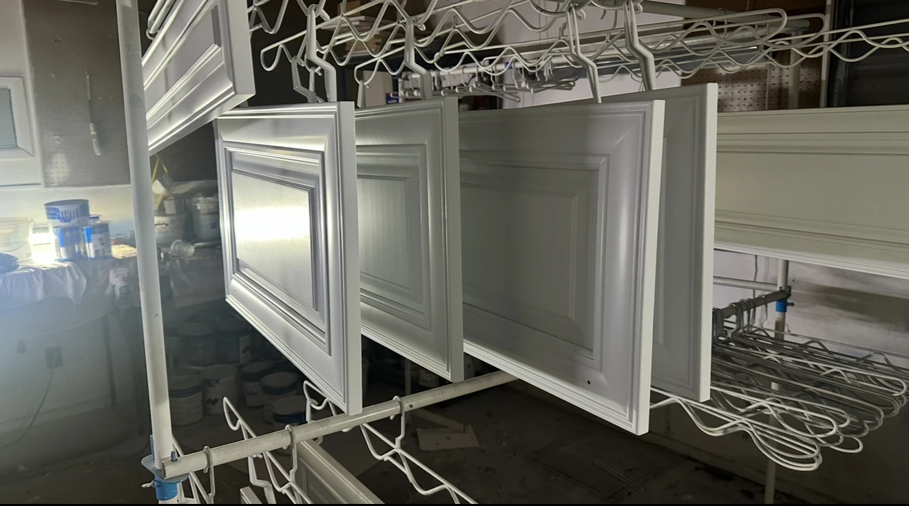 Freshly painted cabinet doors drying on hangers in Sarasota refinishing shop