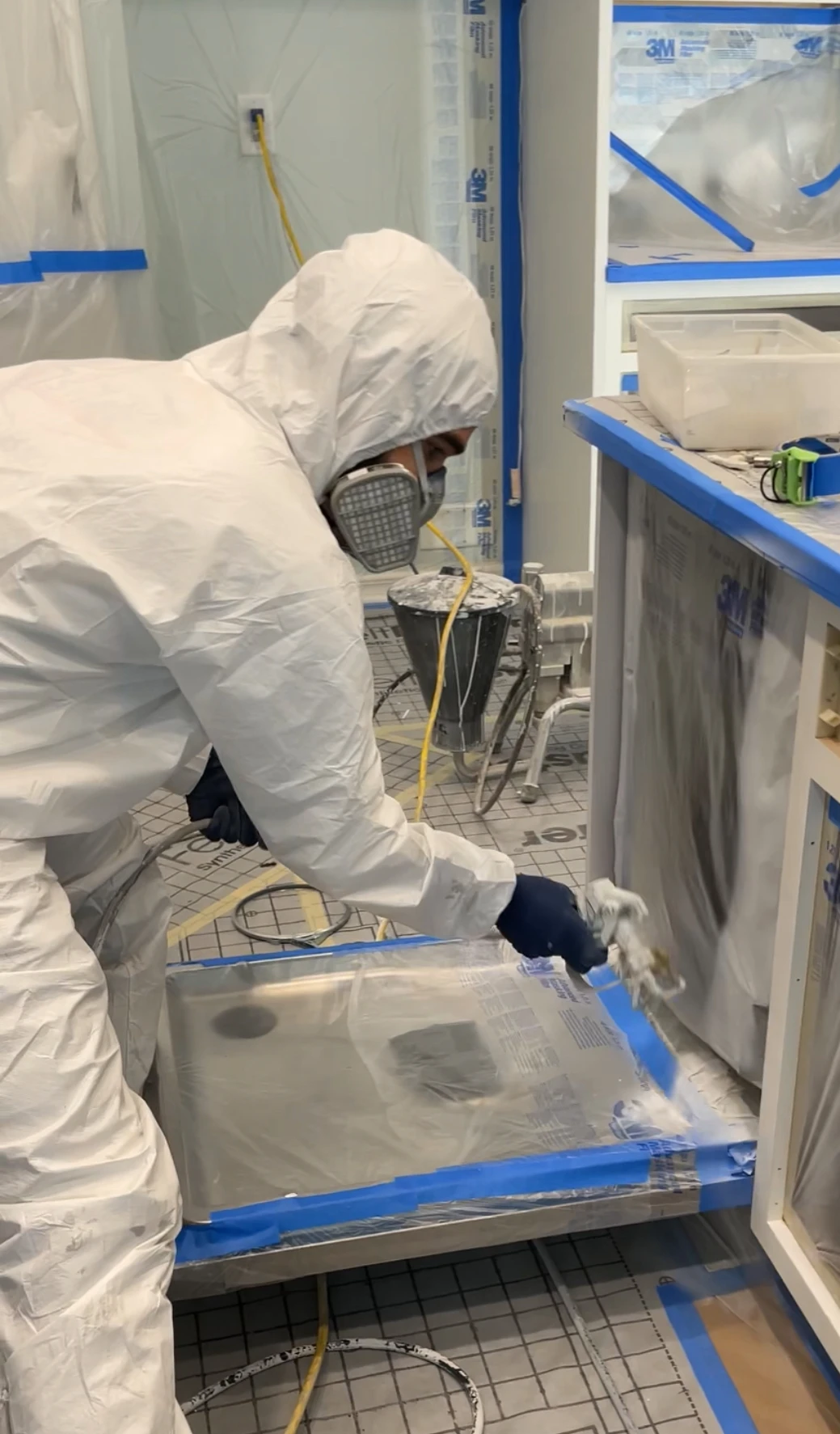 Cabinet painting contractor spraying frames inside Sarasota finishing shop