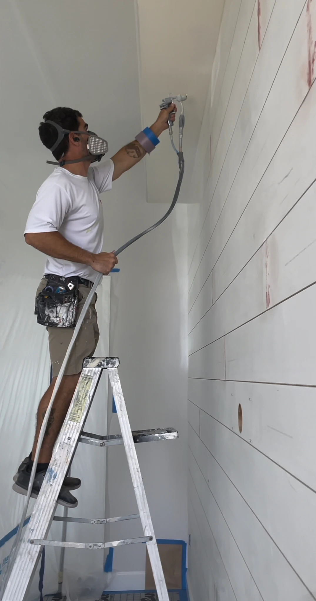 Sarasota painter spraying shiplap accent wall inside coastal living room