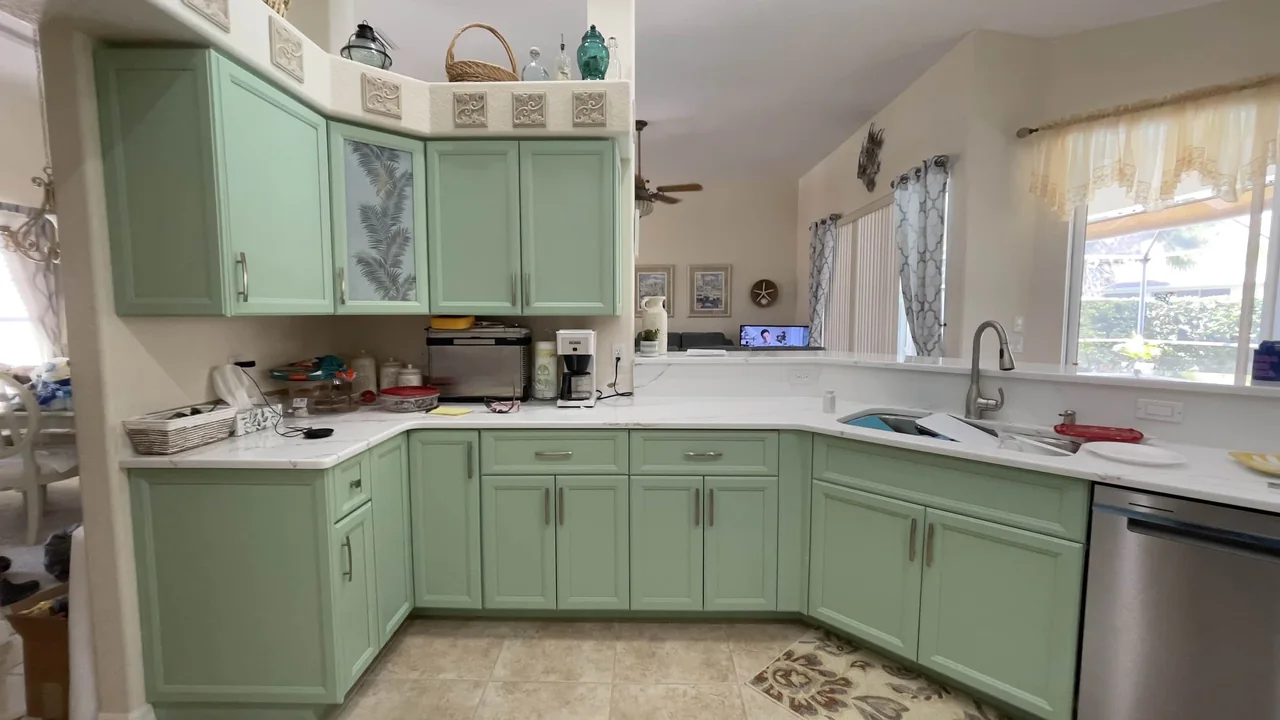 L-shaped kitchen with mint green painted cabinets and white countertops