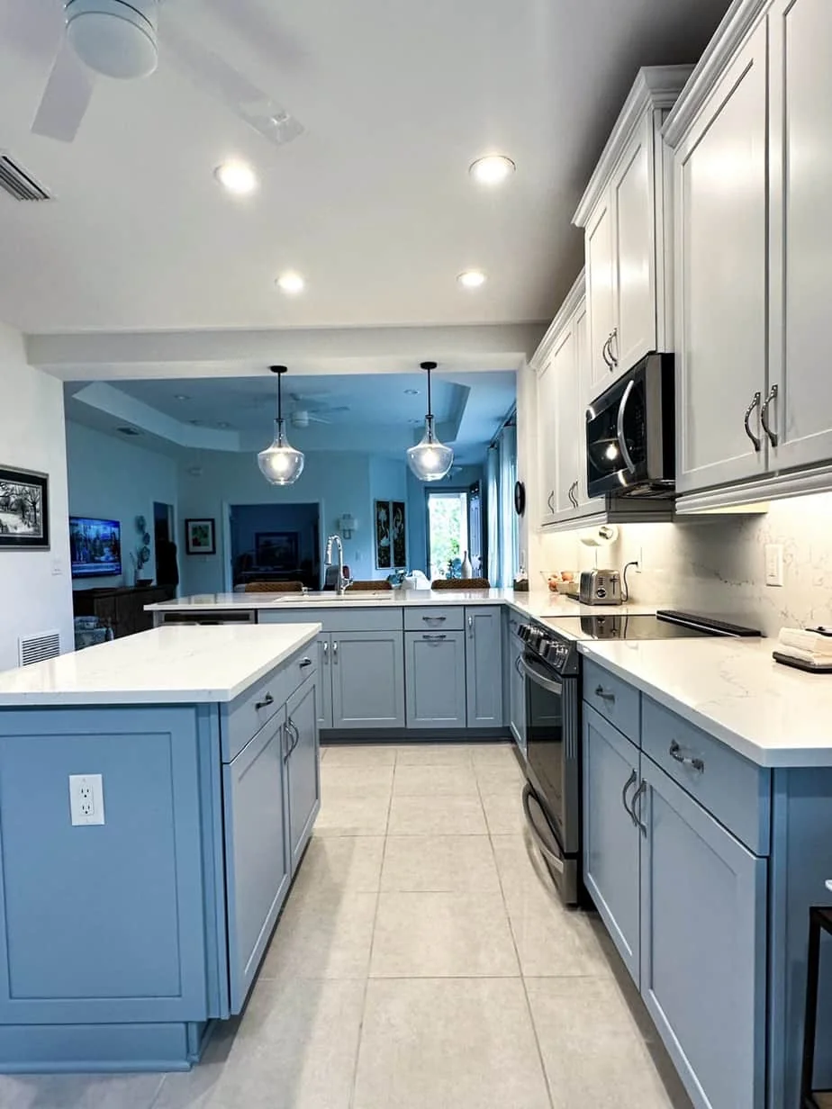 White upper cabinets over blue-gray lower cabinets with a matching island
