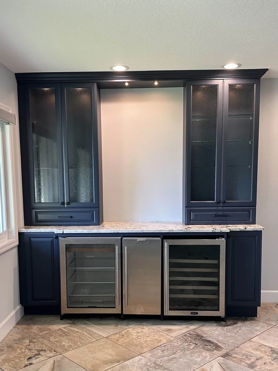 Navy built-in bar cabinets with glass doors above two wine coolers