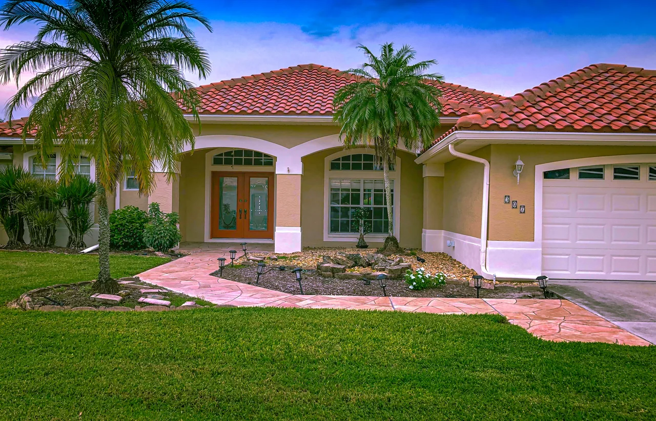 Tan stucco ranch home with white trim and a red tile roof