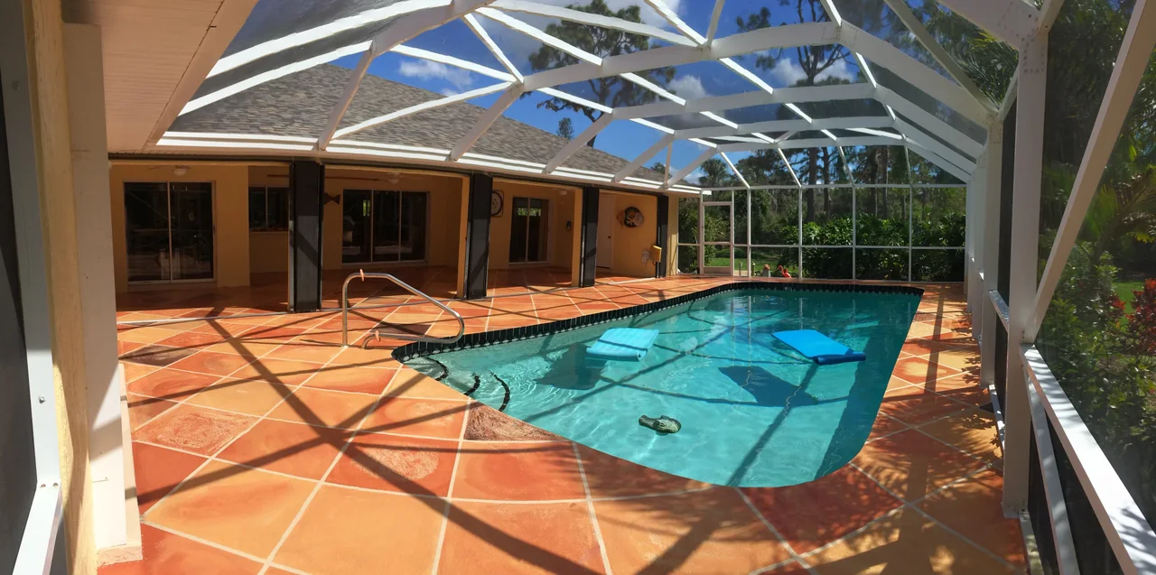 Screened pool enclosure over a terracotta tile pool deck