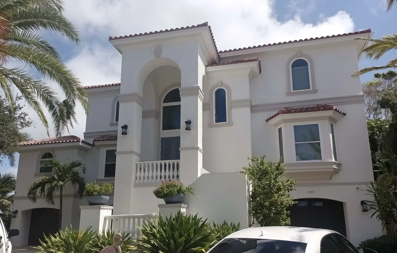 Three-story white stucco home with arched windows and a balcony railing
