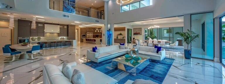 Chic interior design of a spacious, modern living area featuring white sofas, a blue area rug, and a stylish kitchen, highlighting contemporary aesthetics ideal for residential painting projects.